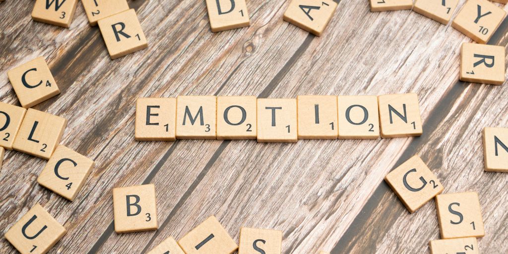 scrabble tiles spelling the word emotion on a wooden surface