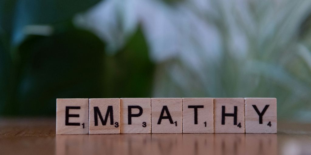 A wooden block spelling the word empathhy on a table