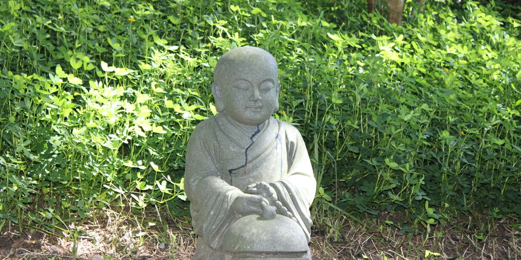 a statue of a buddha sitting in the grass