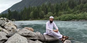 a man sitting on a rock in the middle of a river