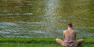 woman in brown tube dress sitting on green grass field near body of water during daytime