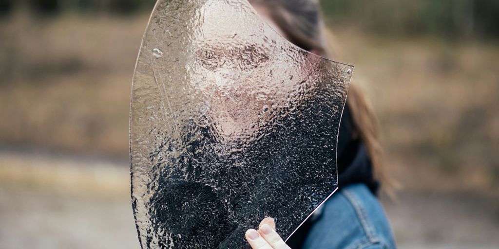 woman covering face with frosted glass